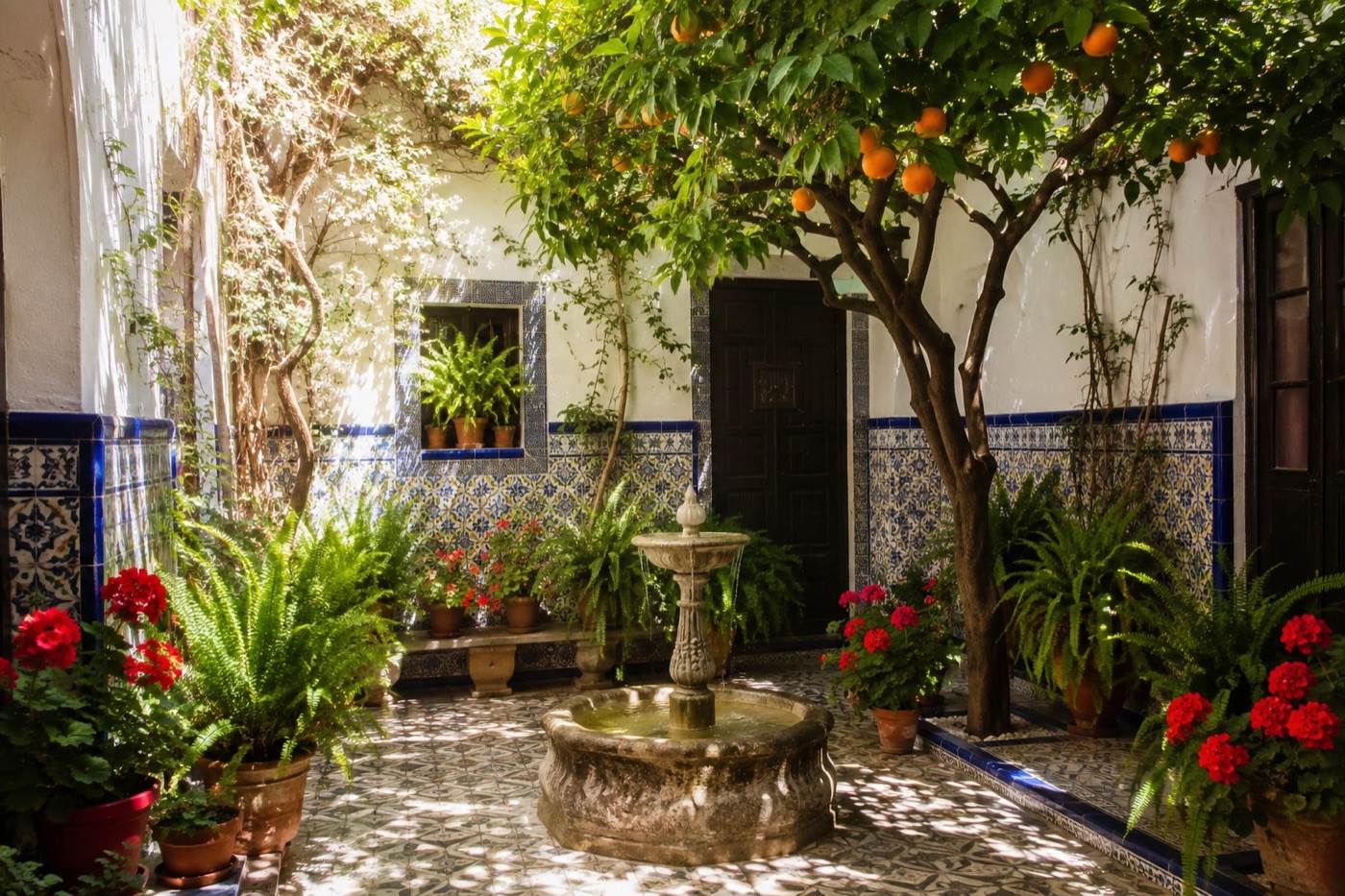 Patio tradicional con naranjo, geranios y fuente